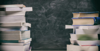 Back to school. Books stacked on black board background